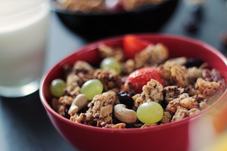 A vibrant red bowl of muesli with fresh fruits and nuts, perfect for a healthy breakfast.